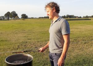 man op foto staat te bbqen op boerencamping